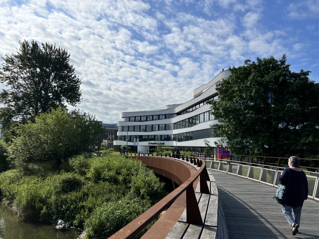 A university building sits ahead of the pedestrian bridge