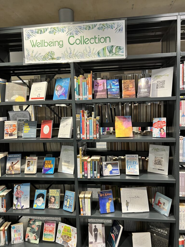 A sign for the 'Wellbeing Collection' sits above the shelves