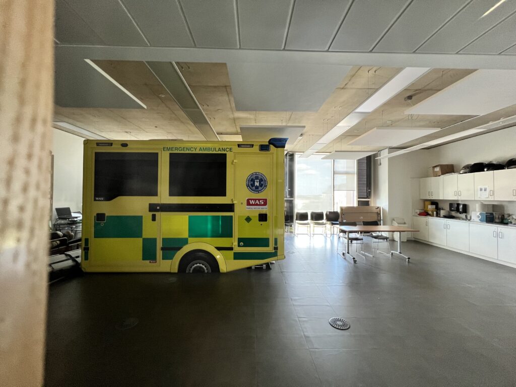 Half of an ambulance sits in the middle of the room.